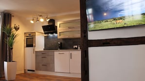 Una cocina moderna con horno empotrado, microondas y un televisor de pantalla plana grande montado en la pared.