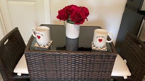 A wicker table with two white mugs featuring red hearts and a vase with red roses. - Paris Suite @Carolina Beach, Walk to Carolina Beach State Park (Carolina Beach)