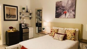 A neatly arranged bedroom with a bed, bedside tables, a dresser, and a wall-mounted shelf with decorative items. - Paris Suite @Carolina Beach, Walk to Carolina Beach State Park (Carolina Beach)