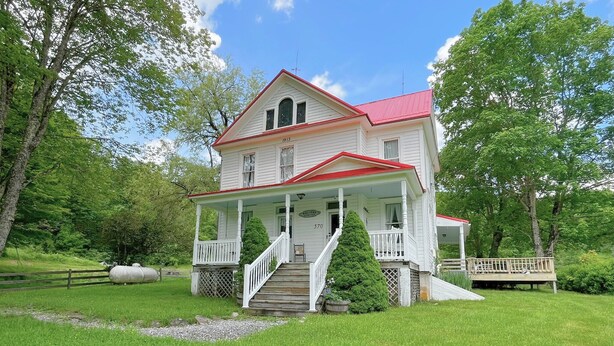 A two-story house with a red roof, a porch, and a staircase leading to the entrance. - Slatyfork Homestead - Cozy Farmhouse Near Snowshoe (Pocahontas County)