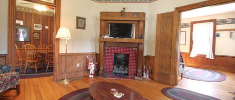 A living room with a fireplace, wooden furniture, and a television.