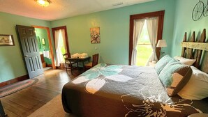 A bedroom with a large bed, a chair, a table with towels, and a bicycle wall decoration. - Slatyfork Homestead - Cozy Farmhouse Near Snowshoe (Pocahontas County)