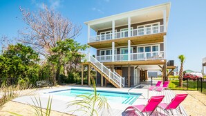 A two-story house with a pool, outdoor seating, and a staircase leading to a balcony. - Sweet Sunshine: Lovely Rental with Pool and Elevator Built in 2021 (Oak Island)