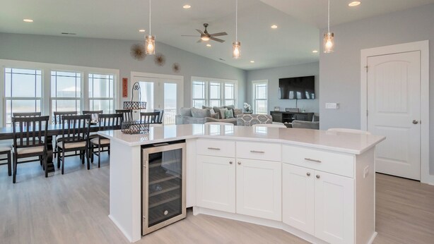 A spacious kitchen with a central island, white cabinetry, and pendant lighting. - Sweet Sunshine: Lovely Rental with Pool and Elevator Built in 2021 (Oak Island)