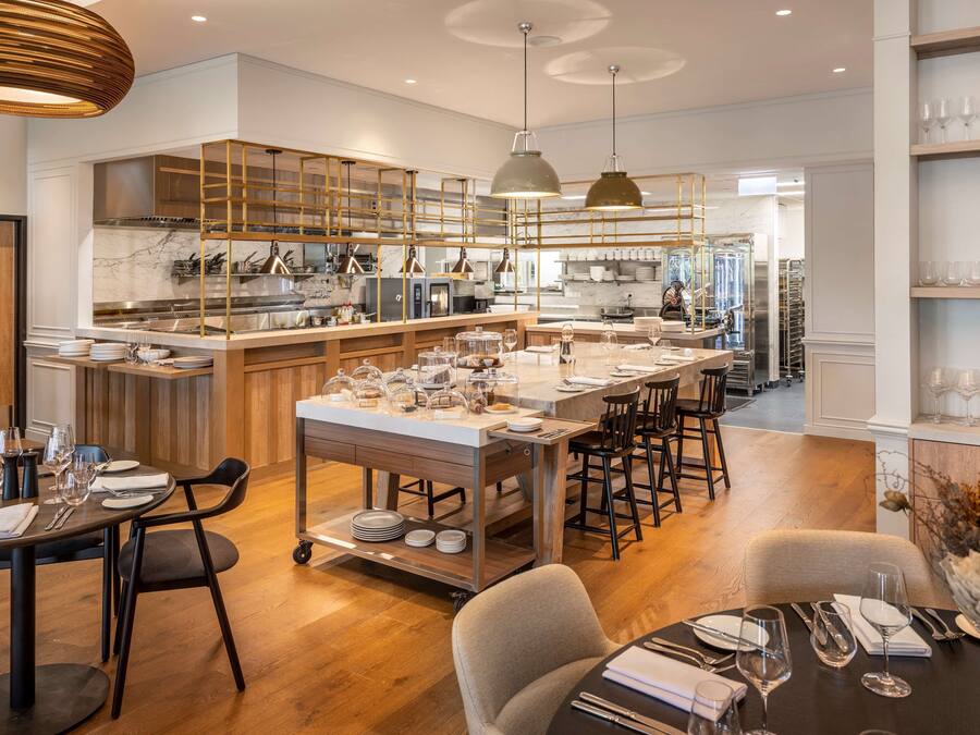 A modern kitchen with a central island, wooden bar counter, and bar stools.