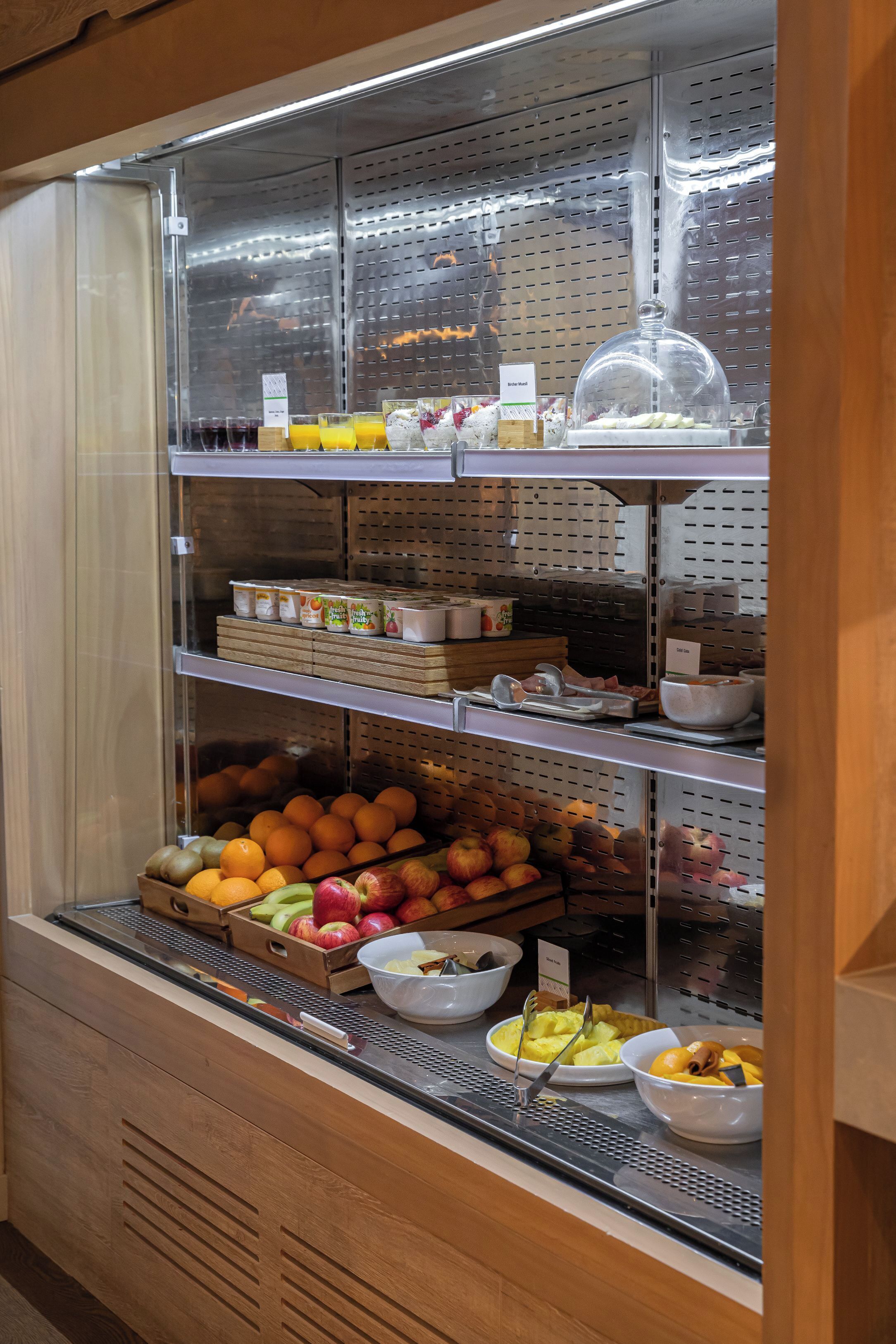 Un angolo colazione a buffet con frutta, cereali e bevande assortite.