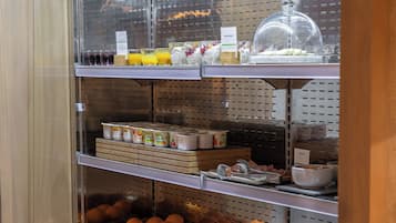 Un angolo colazione a buffet con frutta, cereali e bevande assortite.