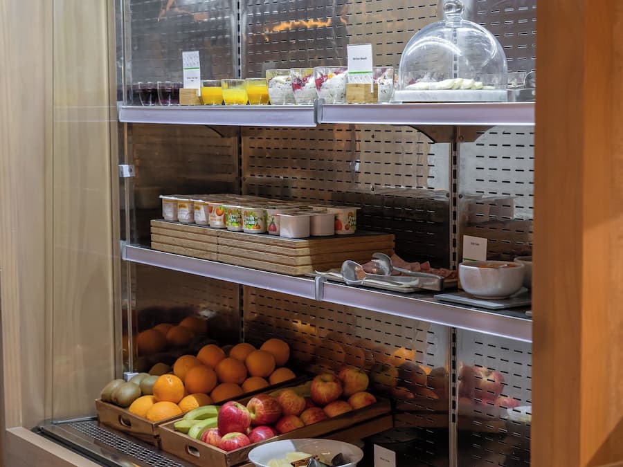 Un angolo colazione a buffet con frutta, cereali e bevande assortite.
