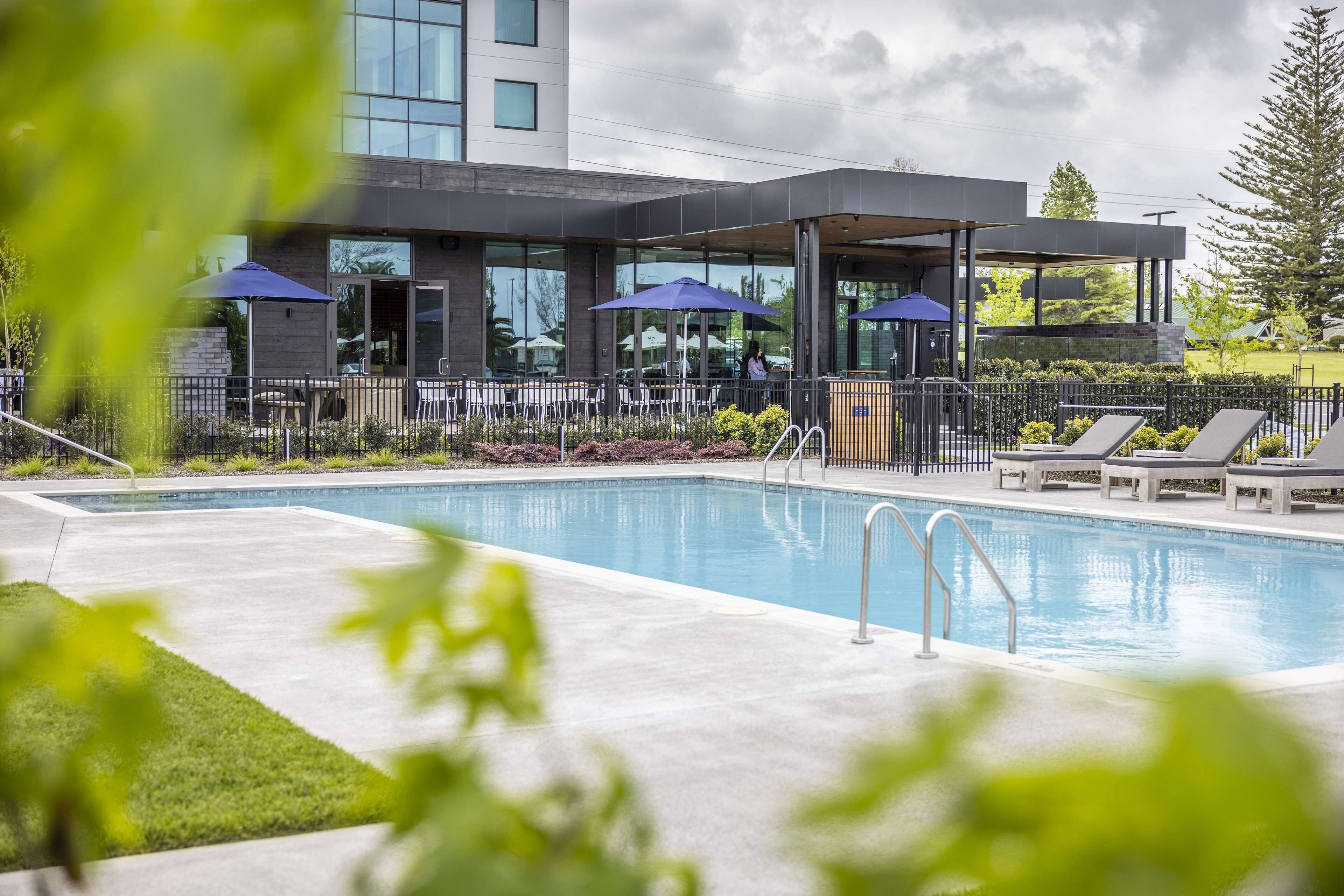Een modern hotel met een zwembad, terras en overdekt patio.