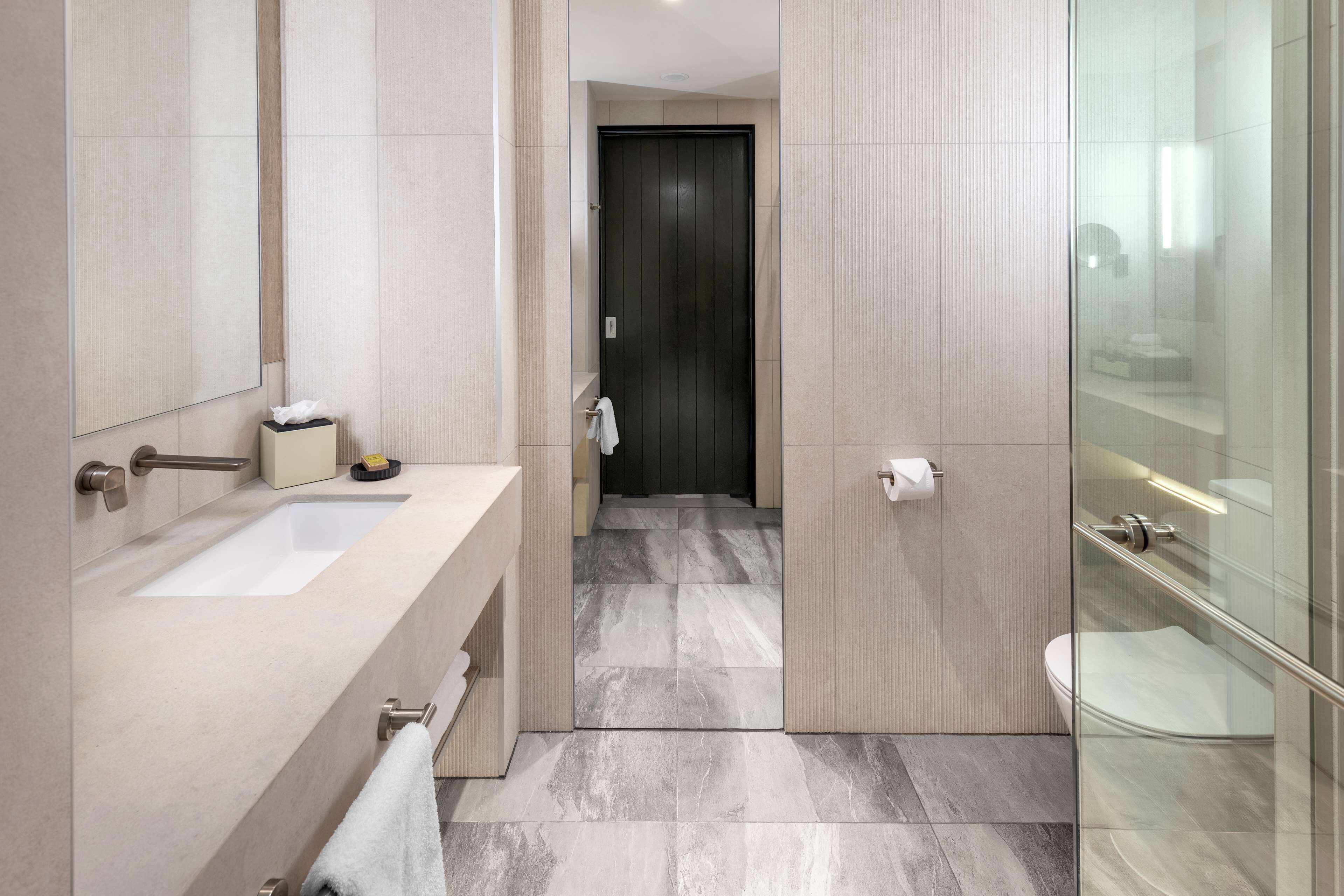 A modern bathroom with a large mirror, a sink, and a glass-enclosed shower area.