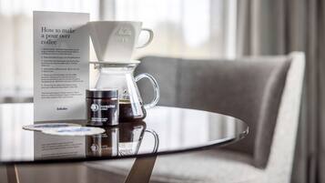 Un appareil à café comprenant une verseuse en verre, une tasse en papier et une dosette de café, le tout posé sur une table.