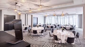 A modern conference room with round tables, black chairs, and a unique ceiling design.