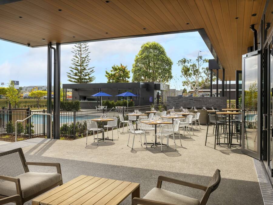 An outdoor patio area with tables and chairs, a pool, and a view of the cityscape.