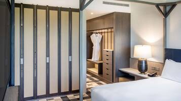 Habitación de hotel con cama, mesita de noche, lámpara, bata y armario.