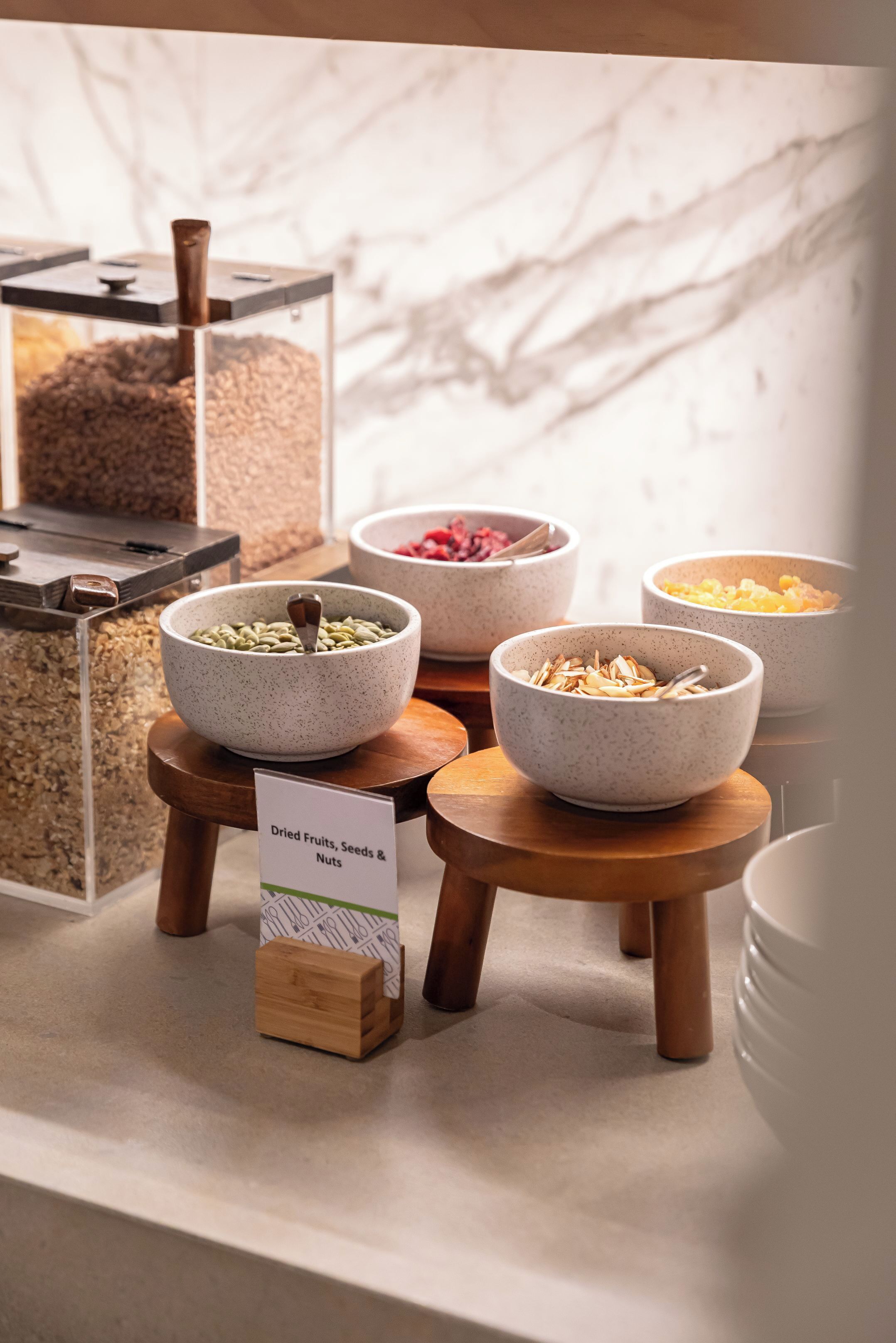 A breakfast buffet with various food items like dried fruits, seeds, and nuts.