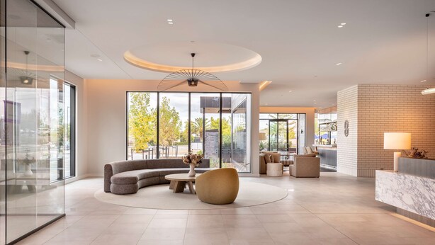 A modern lobby with a curved sofa, round coffee table, and a reception desk. - DoubleTree by Hilton Auckland Karaka (Karaka)