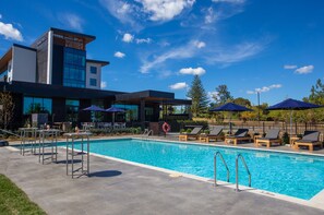 Una piscina al aire libre, sombrillas, sillones reclinables de piscina
