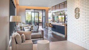 A modern interior with a sofa, a lamp, a dining area, and a bar with a view. - DoubleTree by Hilton Auckland Karaka (Karaka)
