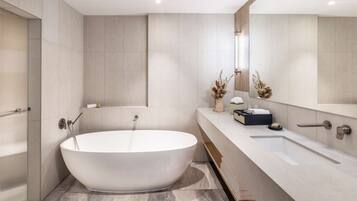A modern bathroom with a freestanding bathtub, a large mirror, and a vanity with a sink.