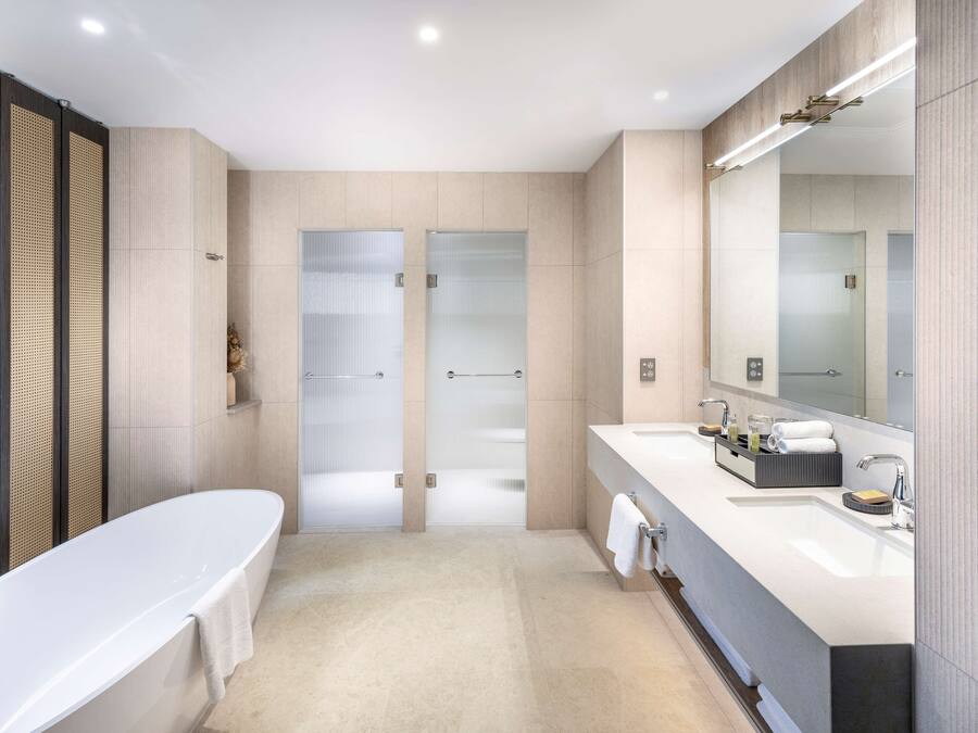 Un baño moderno con una bañera grande, dos lavamanos y un espejo amplio.