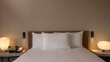 Una habitación de hotel con una cama grande, dos mesitas de noche, un teléfono y lámparas de pared.