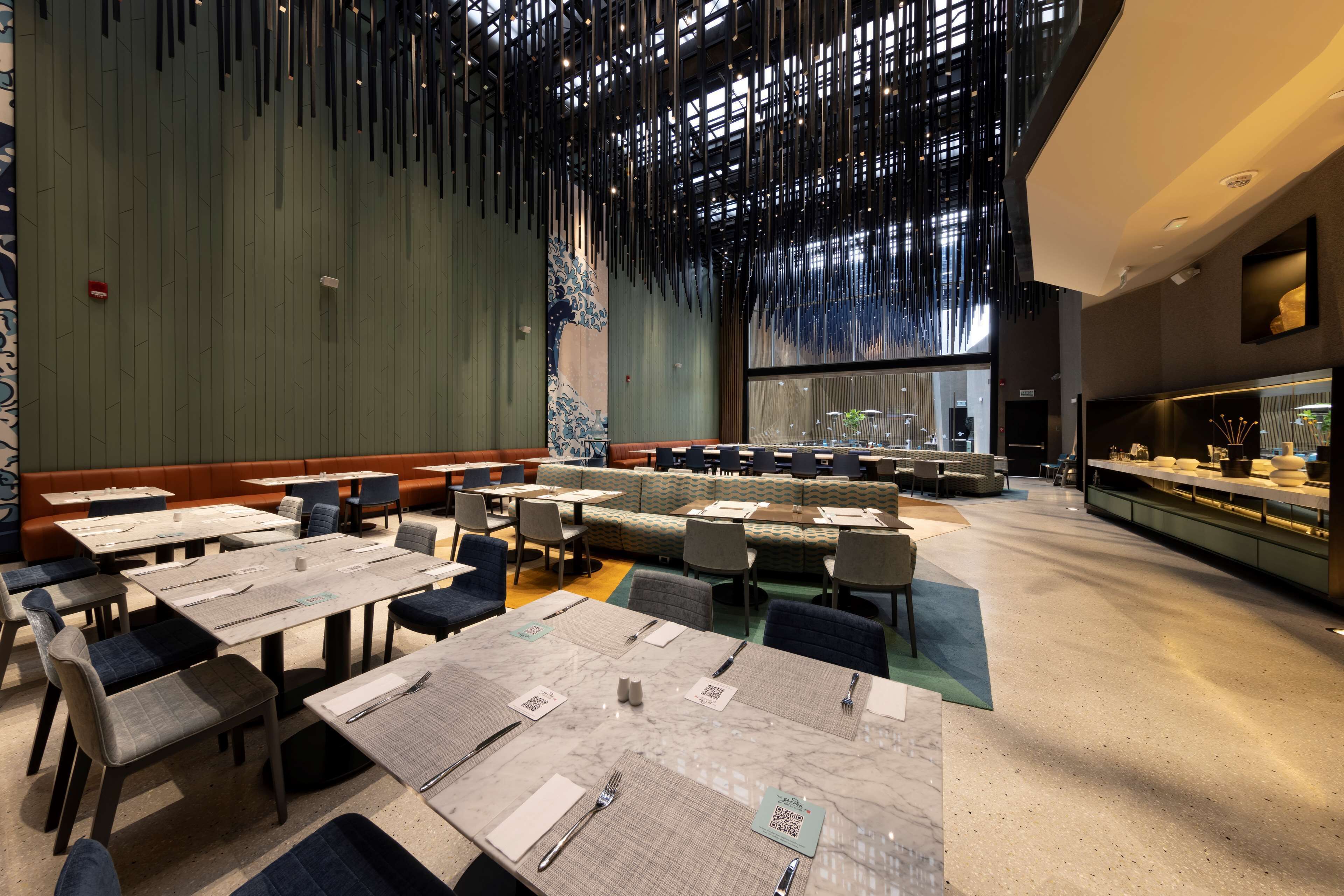A restaurant with multiple dining tables and booths, a bar area, and a decorative ceiling.