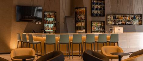 A bar area with modern bar stools, a counter, and shelves of bottles.