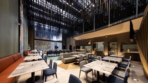 Un restaurante moderno con techos altos, un entrepiso y diversas opciones de asientos, incluyendo mesas y cabinas.