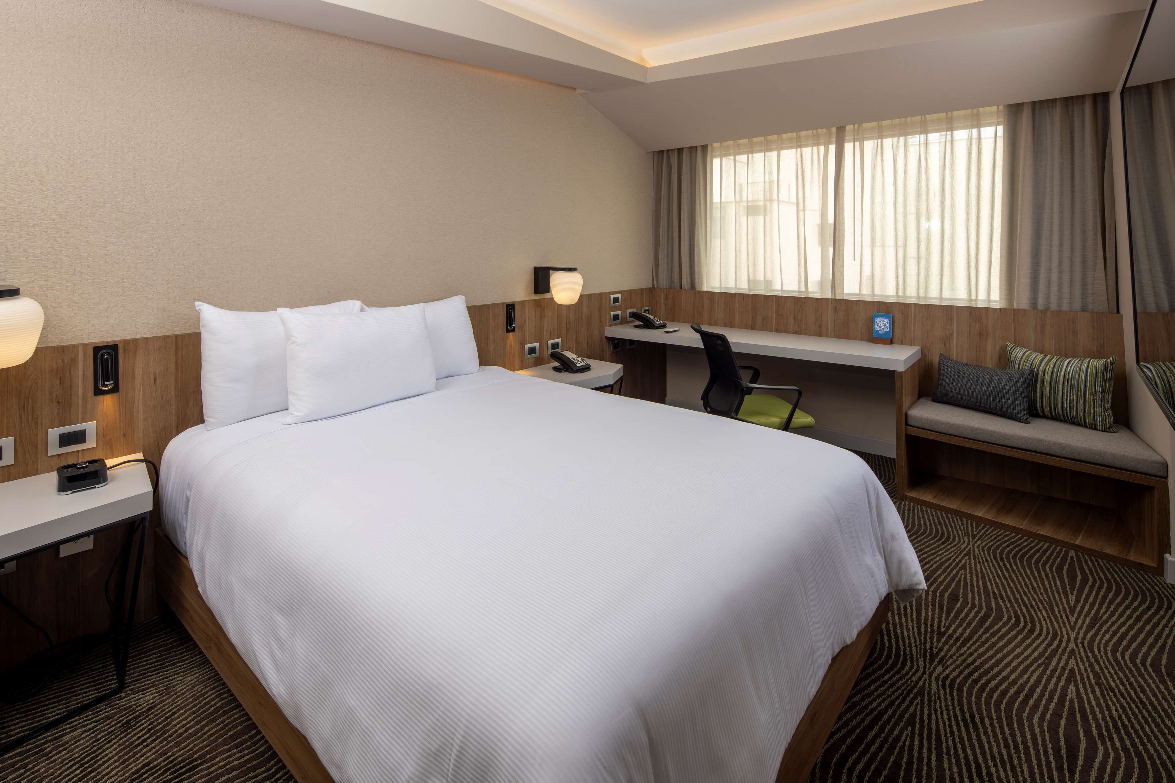 Una camera d'hotel con un letto grande, una scrivania, una sedia e un piccolo angolo salotto.