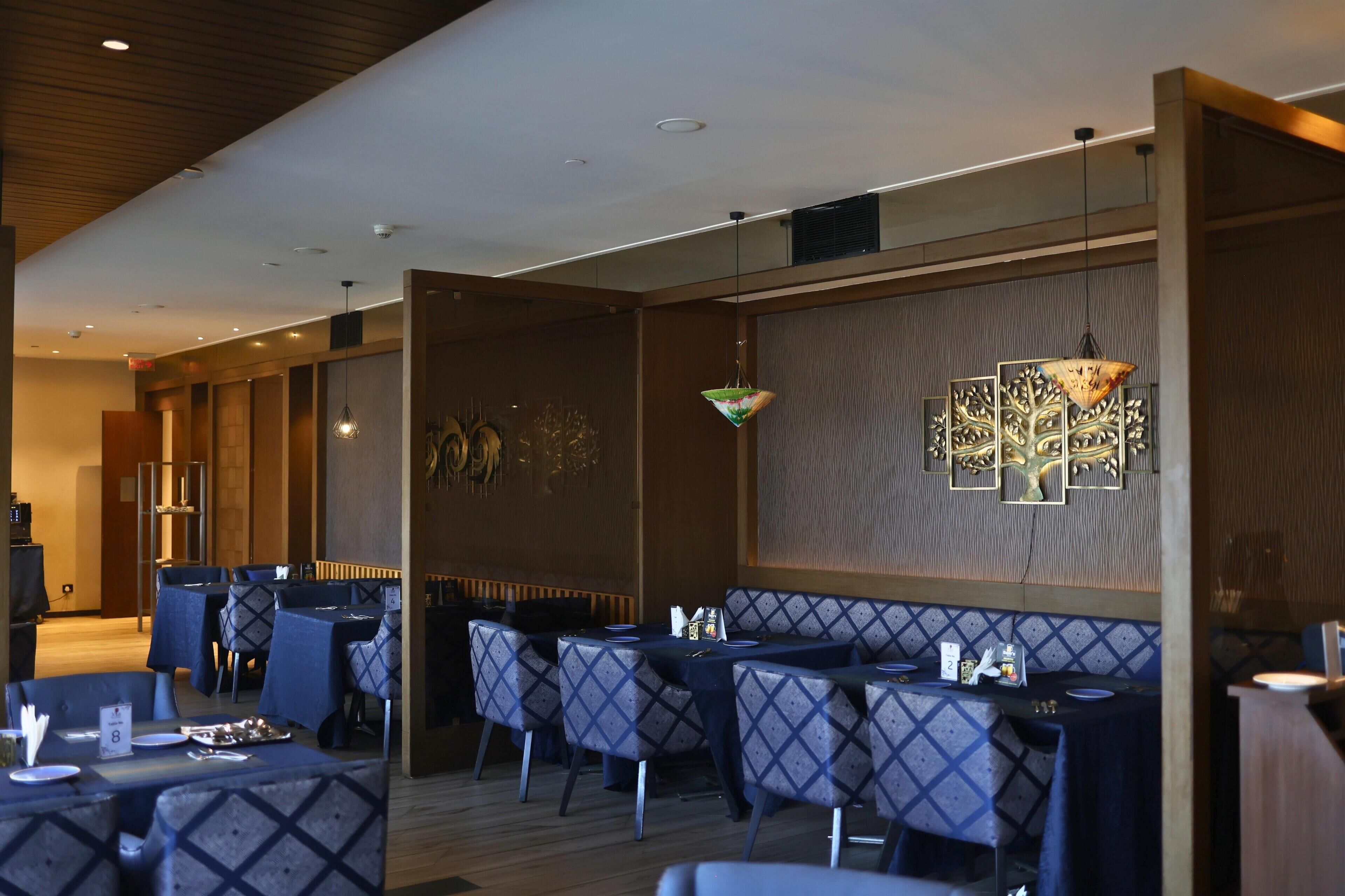 A restaurant with high tables and chairs, a wooden ceiling, and wall-mounted artwork.