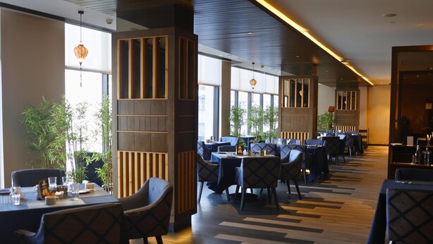 A restaurant with tables, chairs, and potted plants. - Hilton Garden Inn Pune Hinjawadi (Paud)