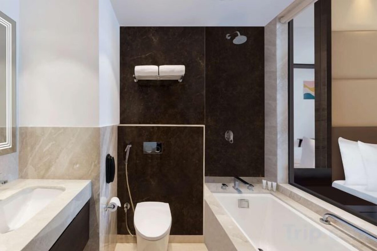 A modern bathroom with a bathtub, toilet, and shower.