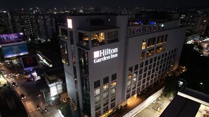 A Hilton Garden Inn building with multiple floors, large windows, and a prominent sign. - Hilton Garden Inn Pune Hinjawadi (Paud)