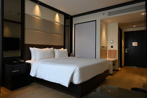 A modern hotel room with a large bed, bedside tables, a desk, and a flat-screen TV. - Hilton Garden Inn Pune Hinjawadi (Paud)