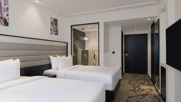 Une chambre d’hôtel avec deux lits, une douche et un couloir menant à une porte.