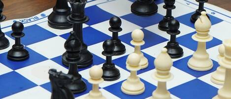 A chessboard with pieces in mid-game, a hand making a move, and a bracelet on the wrist.
