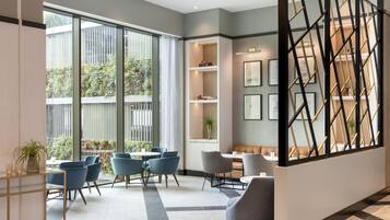 A modern interior with a seating area, large windows, and a staircase.