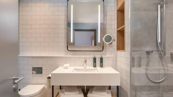 A modern bathroom with a white sink, mirror, and toilet.