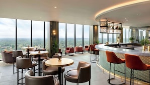 Un bar de altura con vistas panorámicas de la ciudad, muebles modernos y una barra elegante.