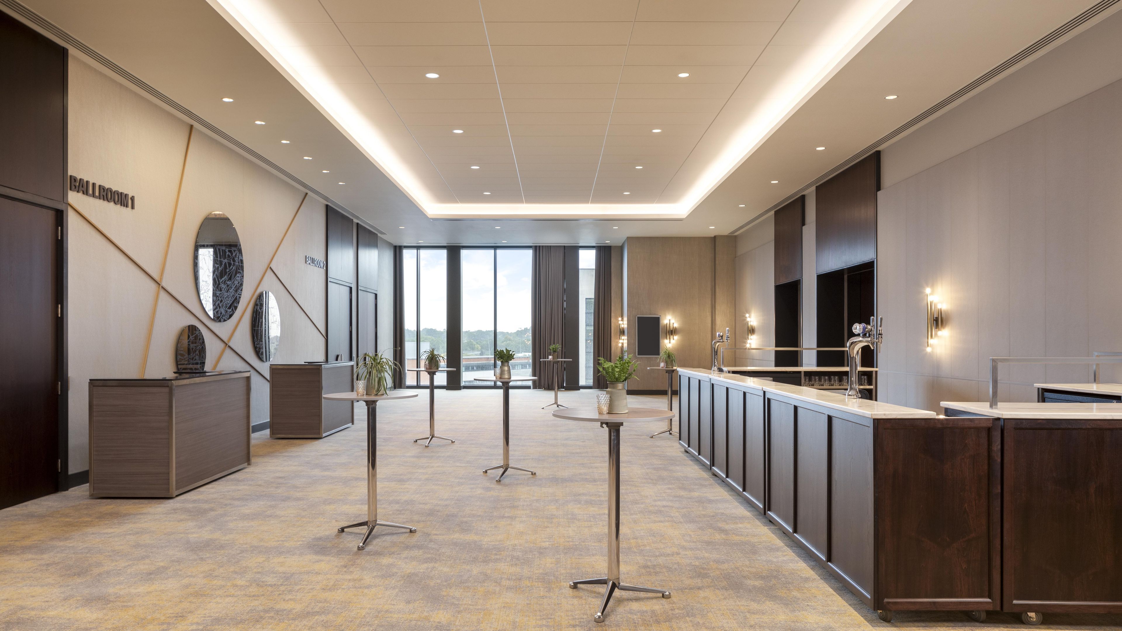 Un moderno vestíbulo de hotel con mostrador de recepción, zona de estar y grandes ventanales con vistas.