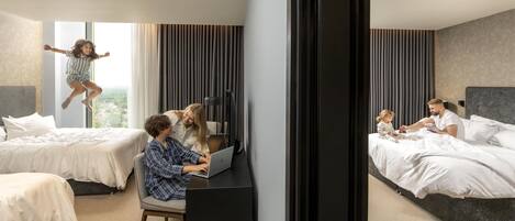 Habitación de hotel con dos camas, un escritorio con una computadora portátil, un televisor y una ventana con cortinas.