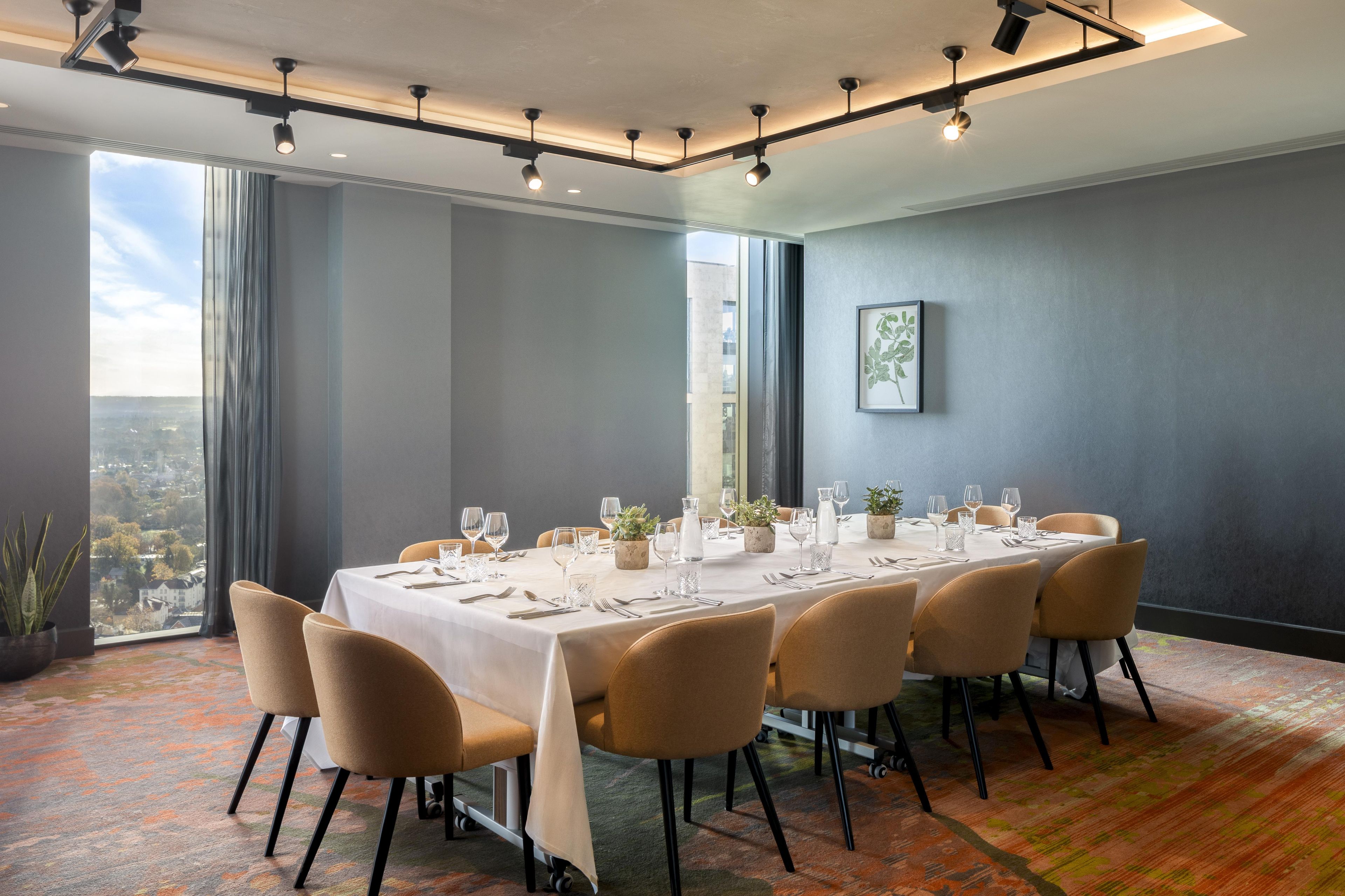 A conference room with a long table set for a meeting, large windows, and a city view.