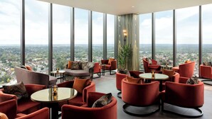 Un salón a varios niveles con diversas zonas de estar, amplias ventanas que ofrecen vistas panorámicas de la ciudad y un diseño interior moderno.