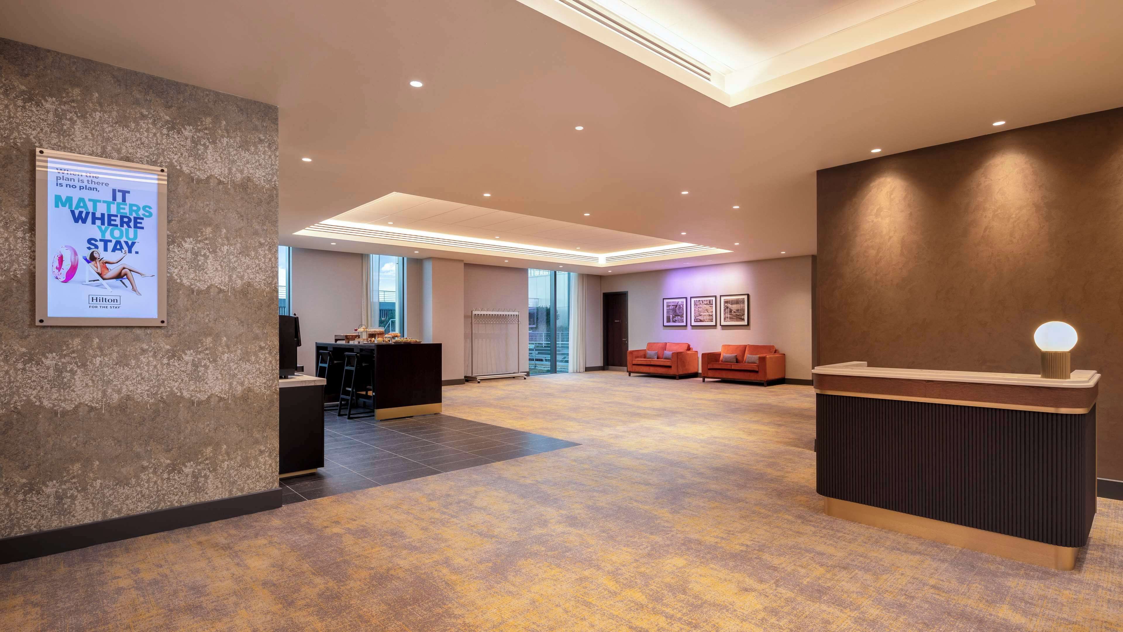 A spacious lobby with a reception desk, seating area, and a large window offering a view of the city.