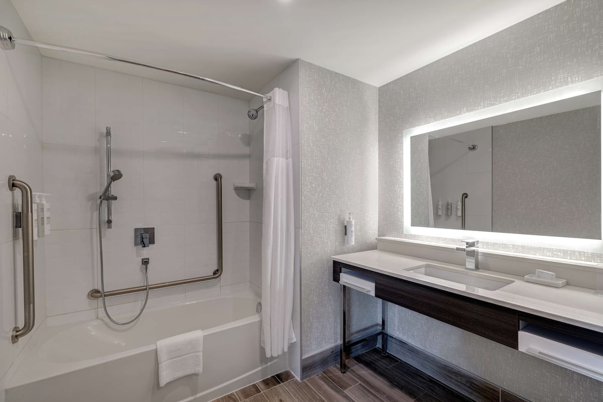 A modern bathroom with a walk-in shower, a large mirror, and a vanity with a sink.