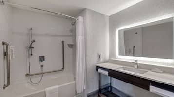 Un baño moderno con cabina de ducha a ras, un espejo grande y un lavamanos.