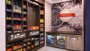 A snack and sundries section with shelves stocked with various packaged snacks and a refrigerated display case. - Hampton Inn & Suites by Hilton Burlington Toronto (Burlington)