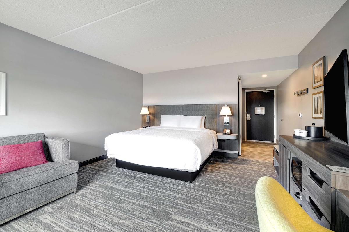 A hotel room with a bed, a sofa, a TV, and a desk.