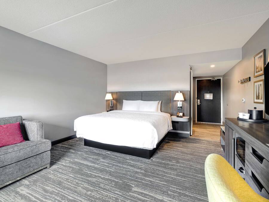 A hotel room with a bed, a sofa, a TV, and a desk.