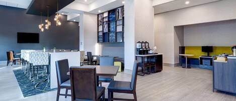 Un hall d’hôtel moderne comprenant un espace repas, un comptoir d’accueil et un bar.